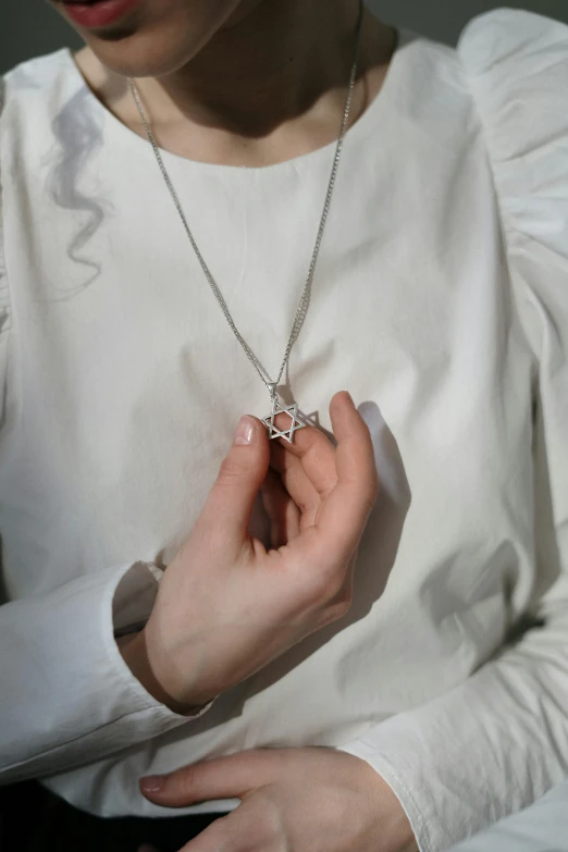 a close up of a person holding a necklace, by Nina Hamnett, stars, square, small, religious