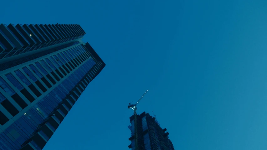 a couple of tall buildings sitting next to each other, a screenshot, by Attila Meszlenyi, pexels contest winner, minimalism, clear blue sky, crane shot, commercial banner, blue