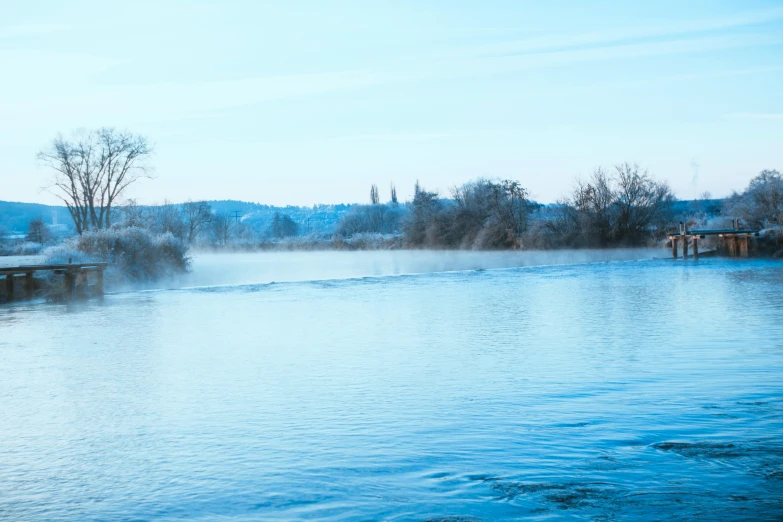 a body of water with a bridge in the background, inspired by William Turner of Oxford, pexels contest winner, romanticism, light blue mist, bucklebury ferry, winter photograph, today\'s featured photograph 4k