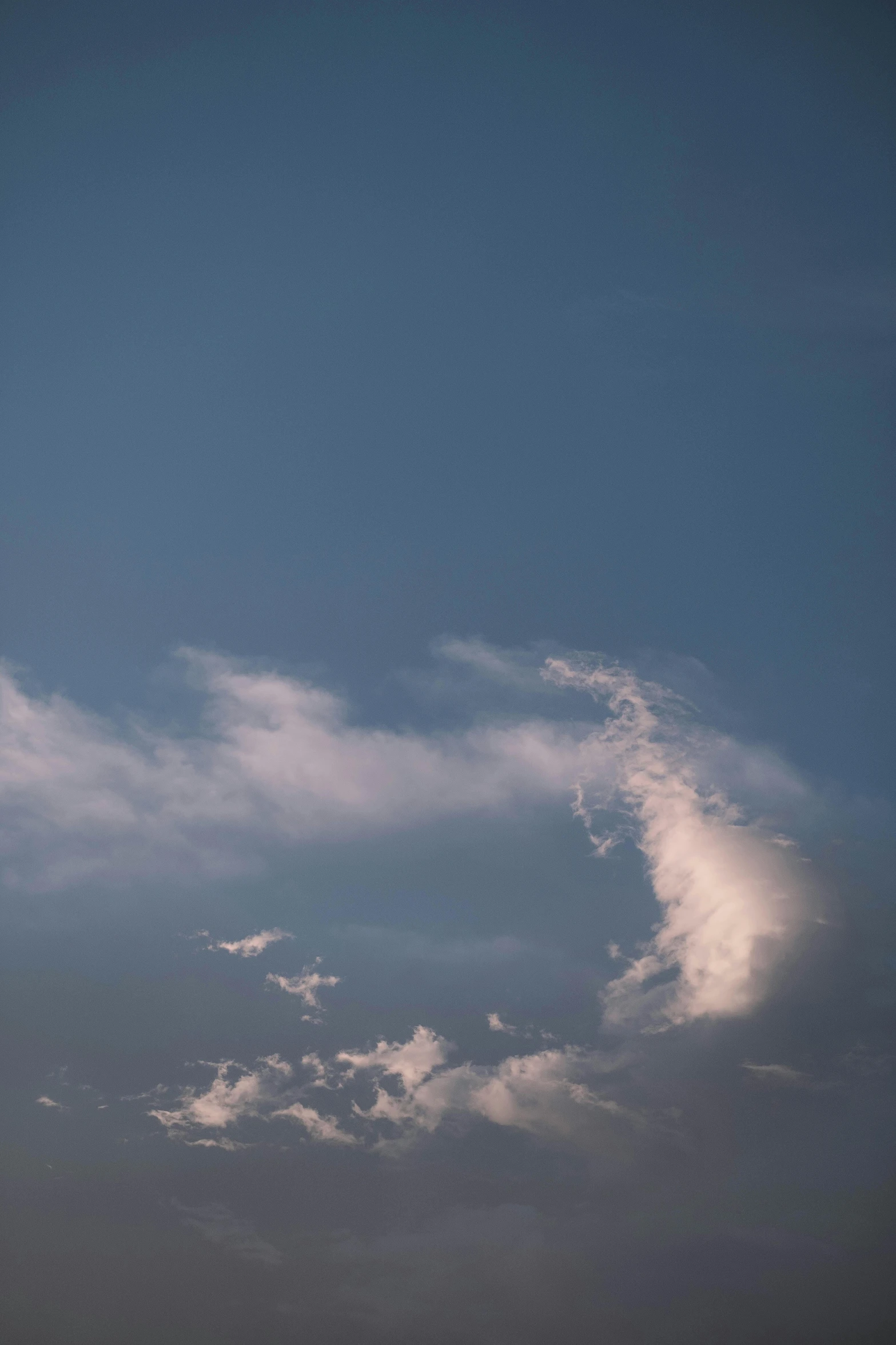 a plane flying through a cloudy blue sky, by Neil Blevins, minimalism, cinematic shot ar 9:16 -n 6 -g, late summer evening, cloud nebula, ignant