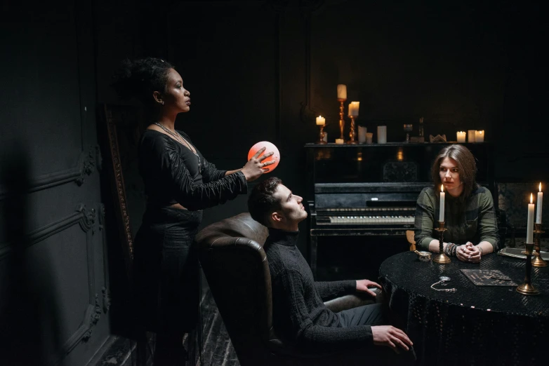 a group of people sitting around a table, a woman holding an orb, spooky lighting, sitting in a lounge, eerie music