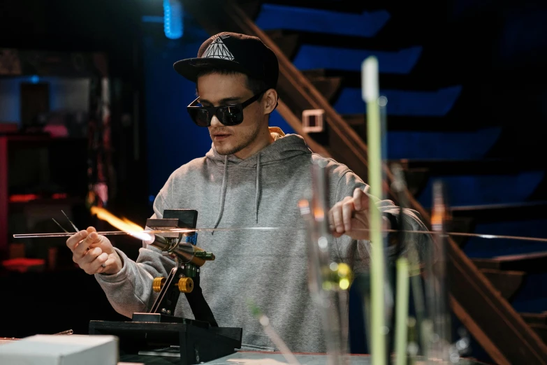 a man is working on a glass sculpture, by Adam Marczyński, pexels, holography, glass and gold pipes, he is in a alchemist lab, wear ray - ban glass, avatar image