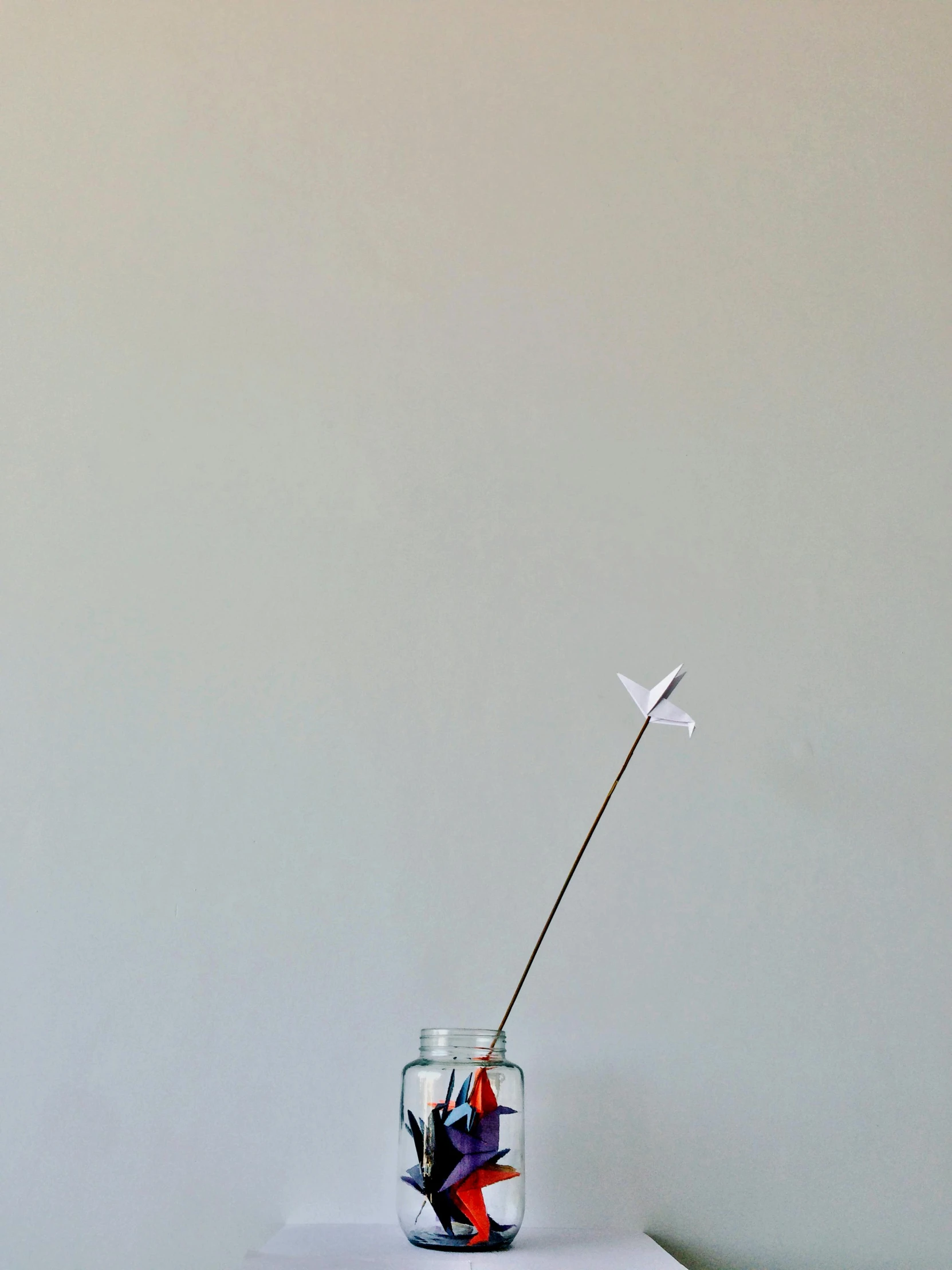 a vase sitting on top of a white table, a minimalist painting, inspired by Alexander Calder, unsplash, kinetic art, cessna glider plane, firework, glass jar, 9 0 mm studio photograph tiny