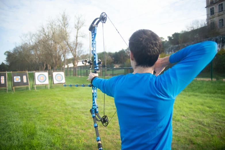 a man that is standing in the grass with a bow, sports setting, instagram picture, viewed from a distance, upper body shot