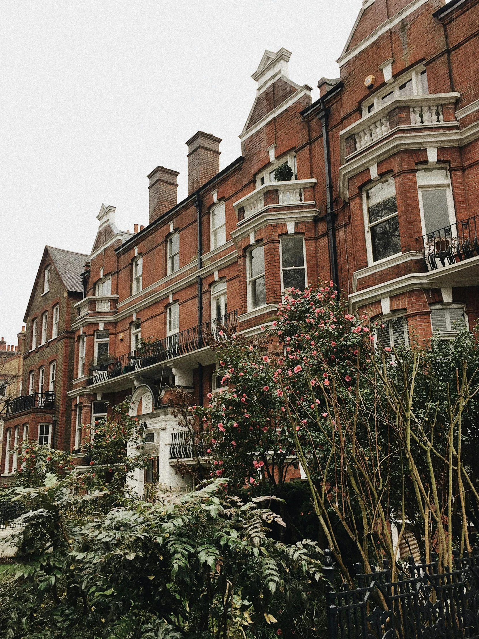 a couple of buildings that are next to each other, unsplash, arts and crafts movement, cold as ice! 🧊, balconies, parks and gardens, on a wet london street