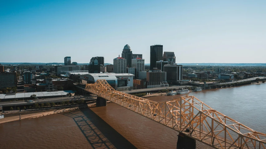 a bridge over a river with a city in the background, by Dan Frazier, pexels contest winner, memphis group, wide high angle view, brown, promotional image