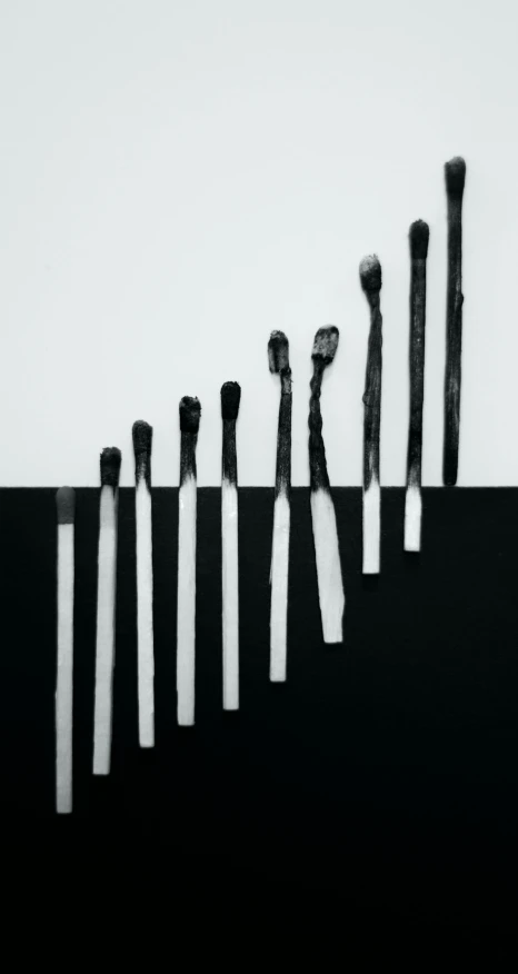 a row of brushes sitting on top of a table, a black and white photo, inspired by Lucio Fontana, unsplash, conceptual art, album cover art, burned, fingers, sergey vasnev