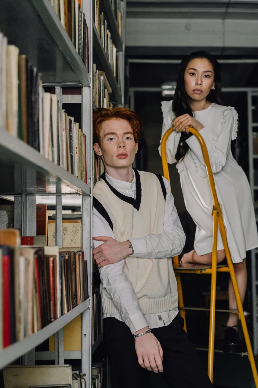 two people standing next to each other in a library, a portrait, trending on pexels, renaissance, brunette boy and redhead boy, asian human, at a fashion shoot, ladders