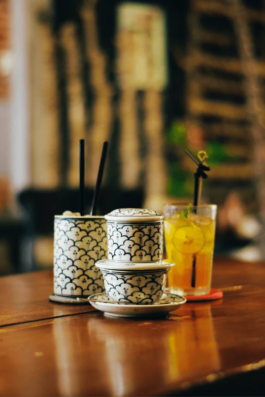 a couple of cups sitting on top of a wooden table, a picture, in style of lam manh, chopsticks, background bar, -n 2