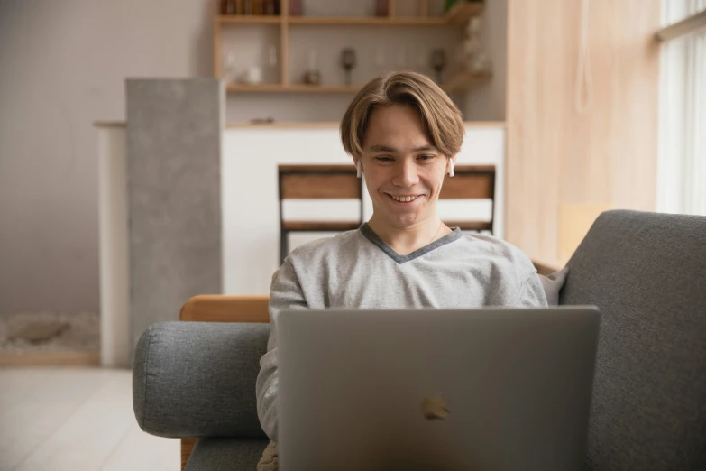 a man sitting on a couch using a laptop, trending on pexels, slightly awkward smile, pokimane, avatar image, student