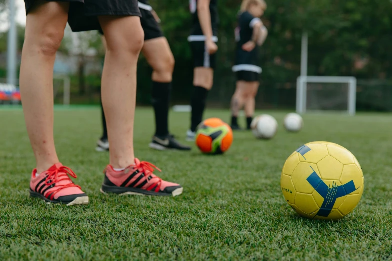 a group of people standing around a soccer ball, on ground