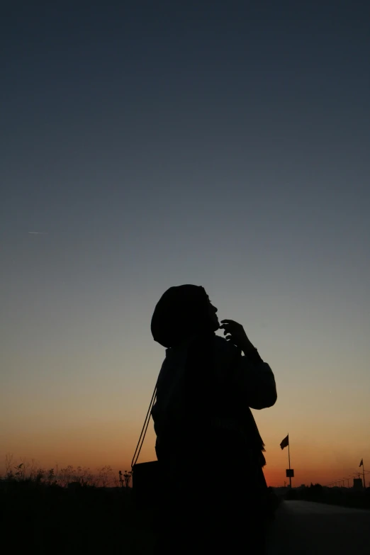 a person taking a picture with a cell phone, by Jan Tengnagel, happening, microphone silluette, looking at the sky, contemplative, taken in the late 2010s