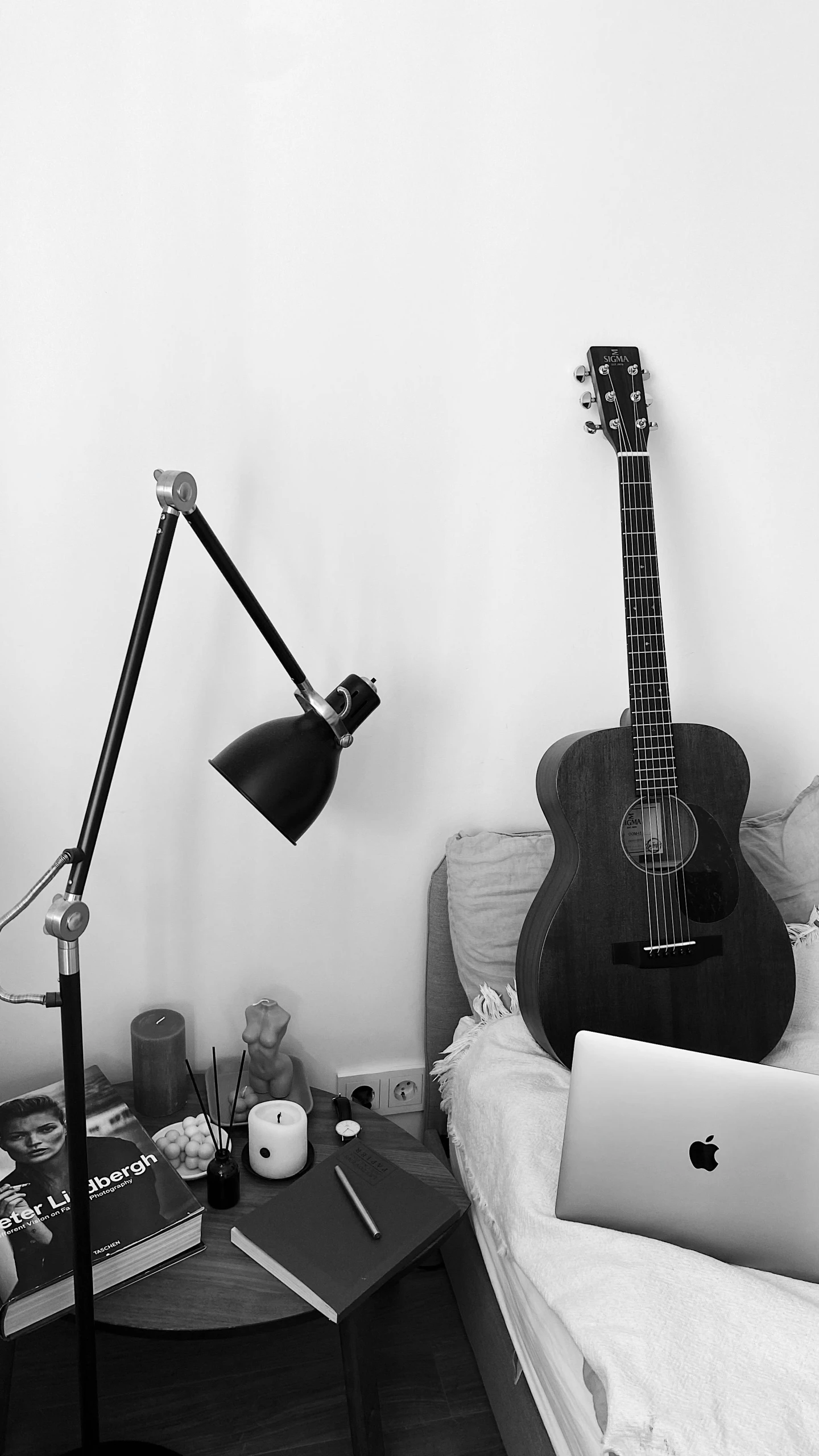 a guitar sitting on top of a bed next to a laptop, by Gavin Hamilton, one single lamp, profile image, instagram photo, monochromatic photo