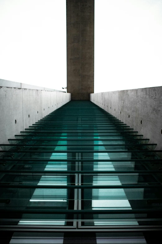 a set of stairs going up to the top of a building, an album cover, inspired by Tadao Ando, unsplash, modernism, glass floor, street of teal stone, liquid glass, sky bridge