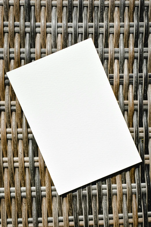 a piece of paper sitting on top of a woven basket, sleek white, outside, blank, detailed product image