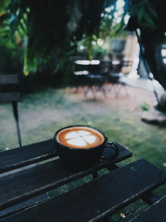 a cup of coffee sitting on top of a wooden table, by Lucia Peka, trending on unsplash, happening, in the garden, latte art, low quality photo, multiple stories