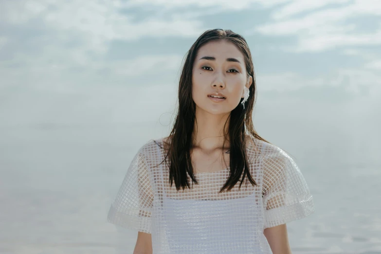 a woman standing in front of a body of water, an album cover, inspired by Kim Tschang Yeul, pexels contest winner, shin hanga, gemma chan girl portrait, in front of white back drop, see - through, summer sky