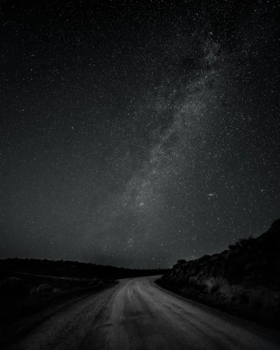 a black and white photo of the milky over a dirt road, starry sky 8 k, 2 5 6 x 2 5 6 pixels, hilly road, sarah cliff