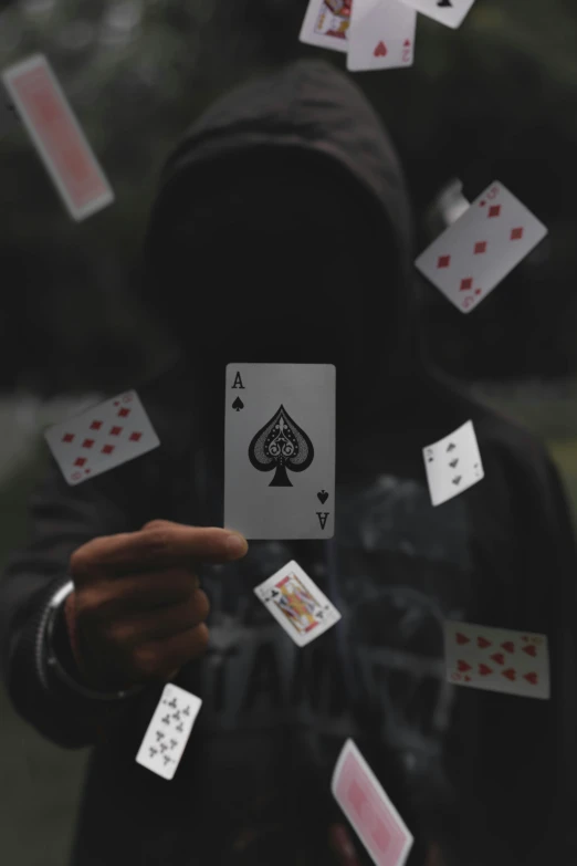 a person in a hoodie holding playing cards, pexels contest winner, ( ( theatrical ) ), splash image, a black cloak, an intruder