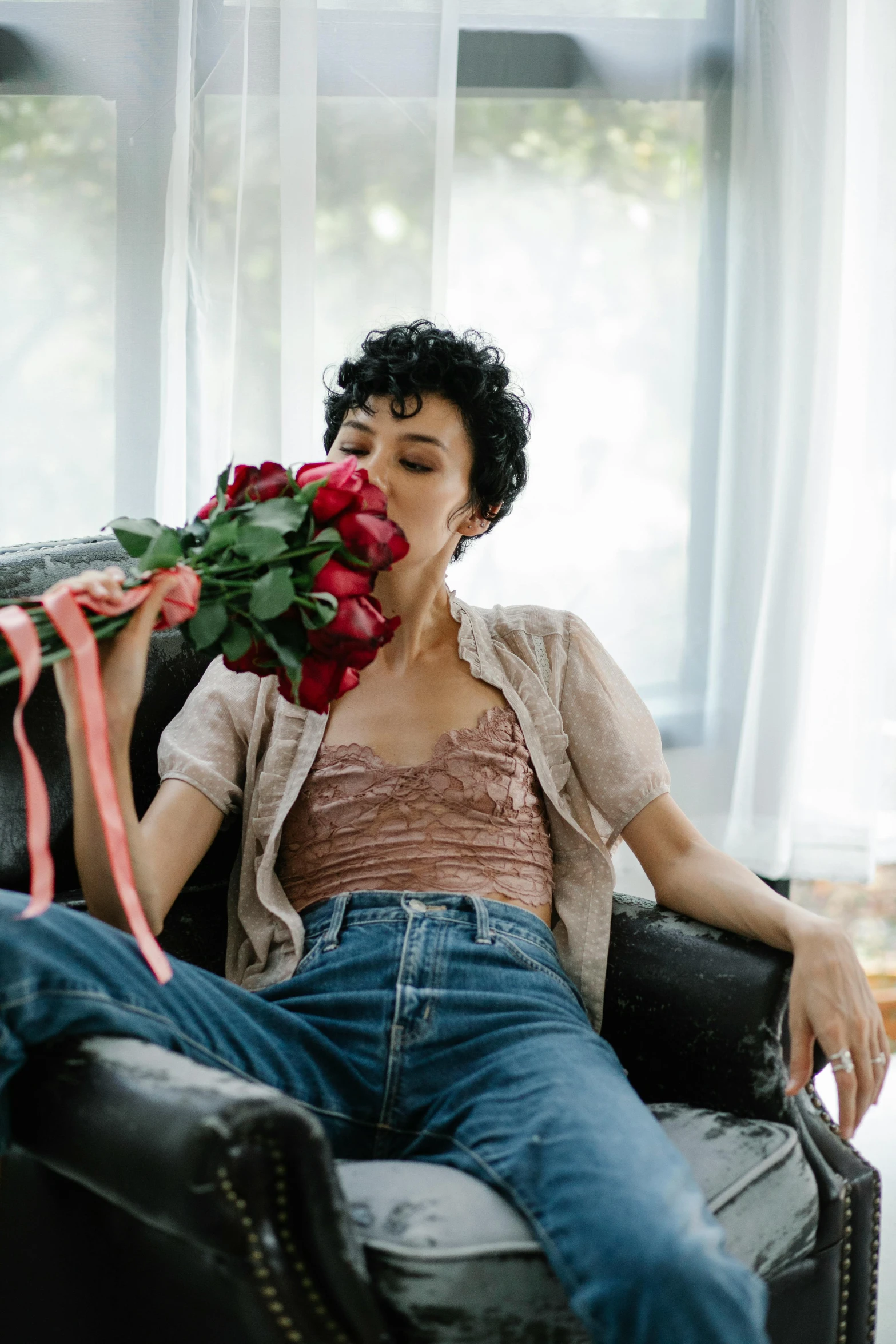 a woman sitting in a chair holding a bouquet of flowers, by Winona Nelson, pexels contest winner, romanticism, curly pixie cut hair, making out, on a couch, maggie cheung