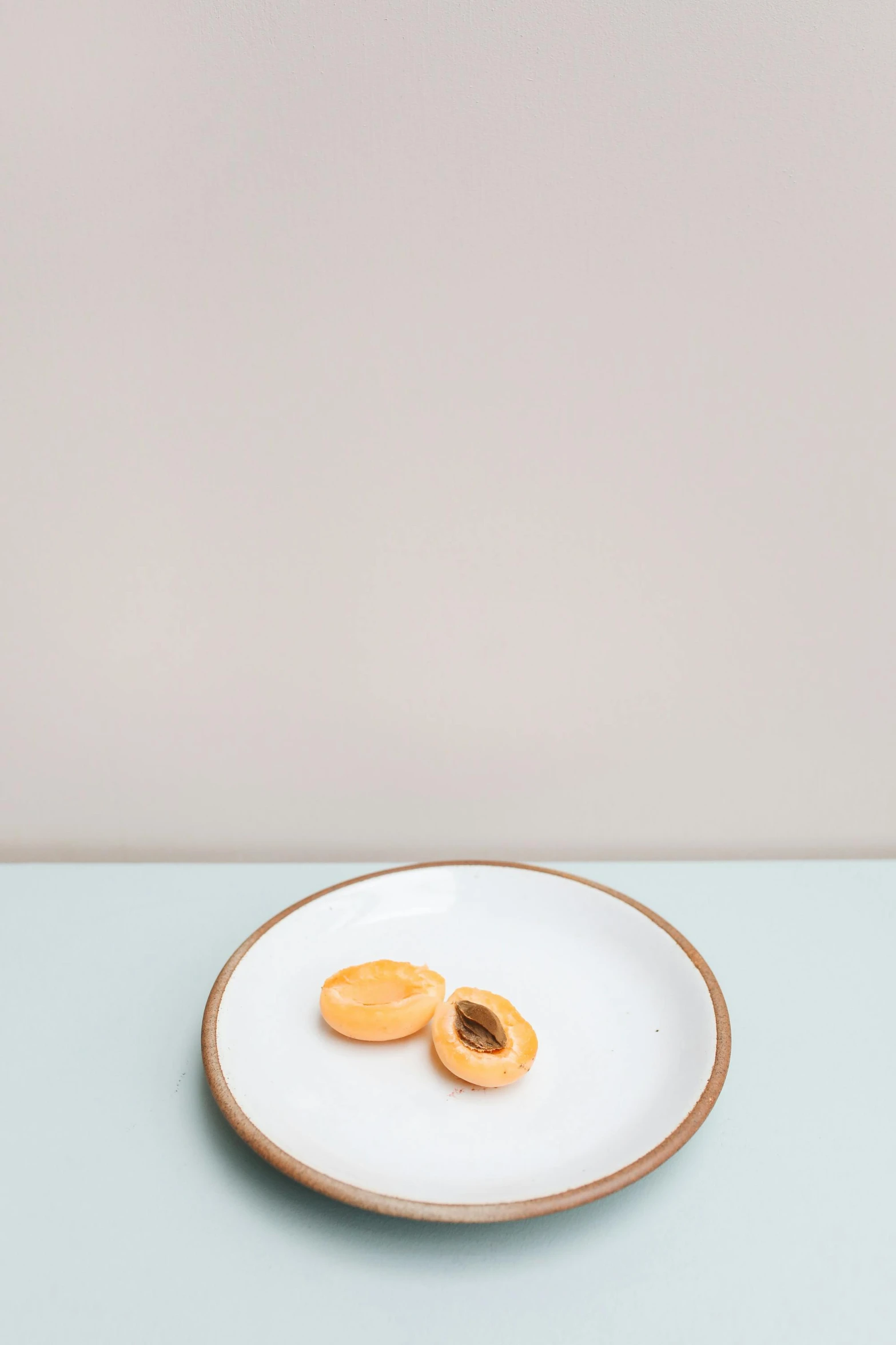 a plate with two pieces of apricots on it, by Harvey Quaytman, minimalism, smooth porcelain skin, natural soft rim light, 4l, two tone