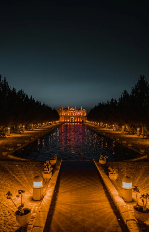 a long walkway next to a body of water at night, by Abdullah Gërguri, gardens and fountains, iran, low quality photo, symmetrical image