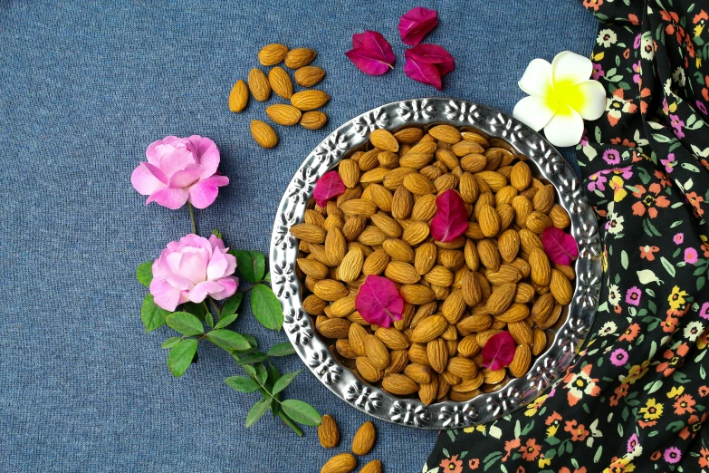 a bowl of almonds and flowers on a table, inspired by Li Di, pexels, dau-al-set, background image, aluminum, kerala motifs, thumbnail