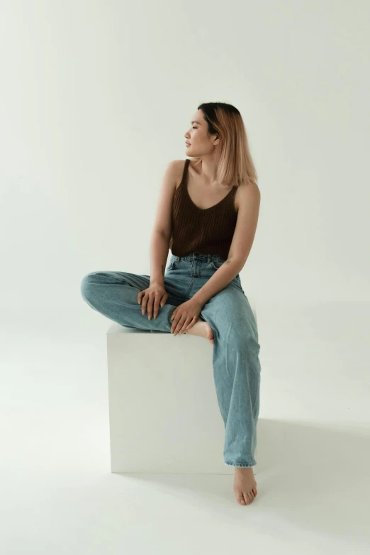 a woman sitting on top of a white box, baggy jeans, wearing : tanktop, louise zhang, muted browns