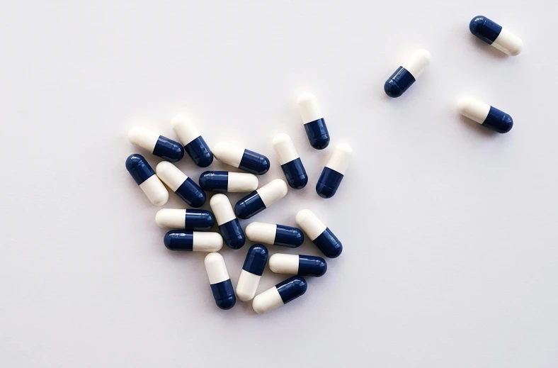 a heart made out of blue and white pills, an illustration of, unsplash, antipodeans, alien capsules, on a white table, navy, minimalist photorealist