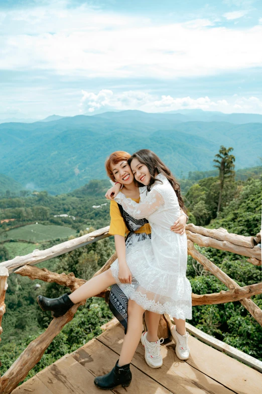 a couple of women sitting on top of a wooden platform, a picture, inspired by Ruth Jên, pexels contest winner, sumatraism, hugging, in a scenic background, square, dang my linh