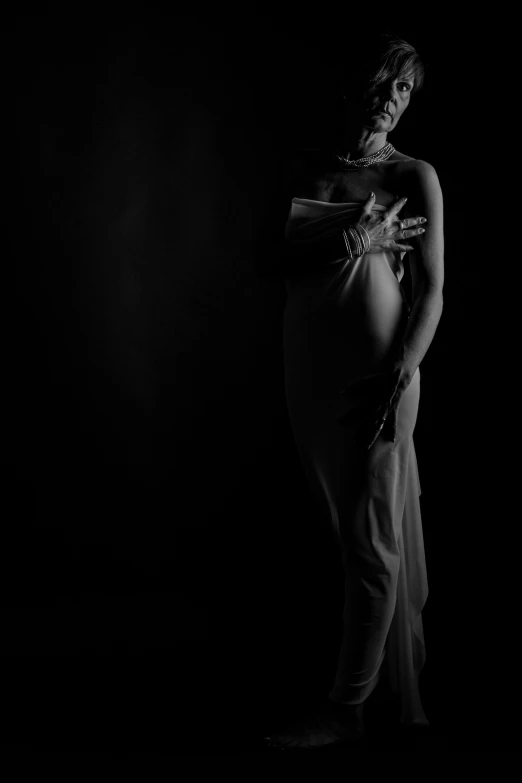 a black and white photo of a pregnant woman, inspired by Lillian Bassman, figurative art, black backdrop, holding close, dramatic lighting - n 9, entire body