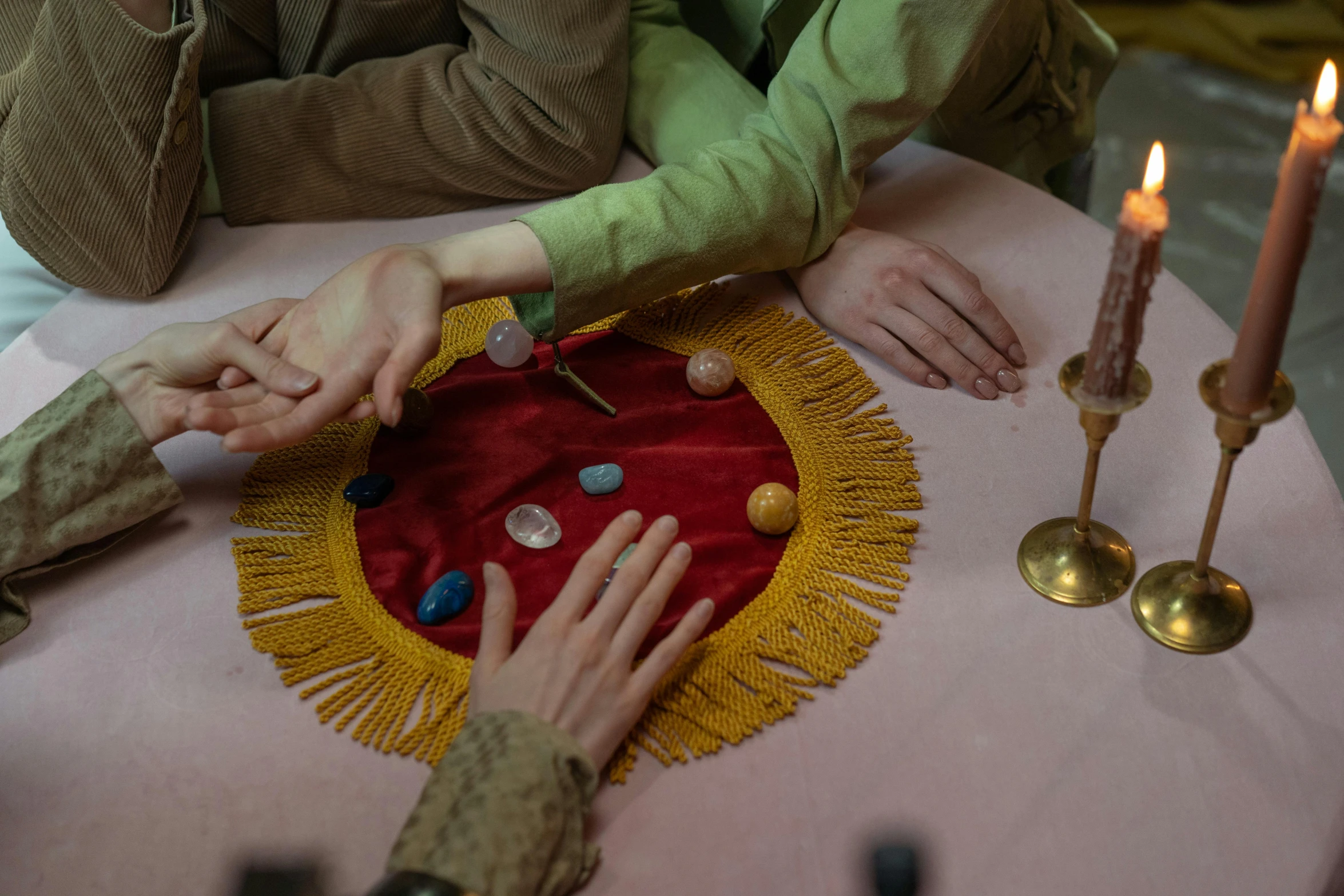 a couple of people that are sitting at a table, by Elsa Bleda, process art, summoning circle, red and gold cloth, embedded with gemstones, wes anderson film