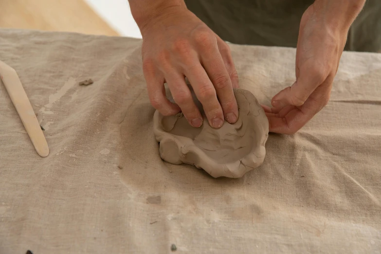 a person is making a clay sculpture on a table, inspired by Sarah Lucas, instagram, paw pads, sand swirling, portrait no. 1, hanging