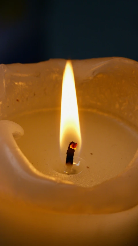 a lit candle sitting on top of a table, birdseye view, burning down, centred, white wax