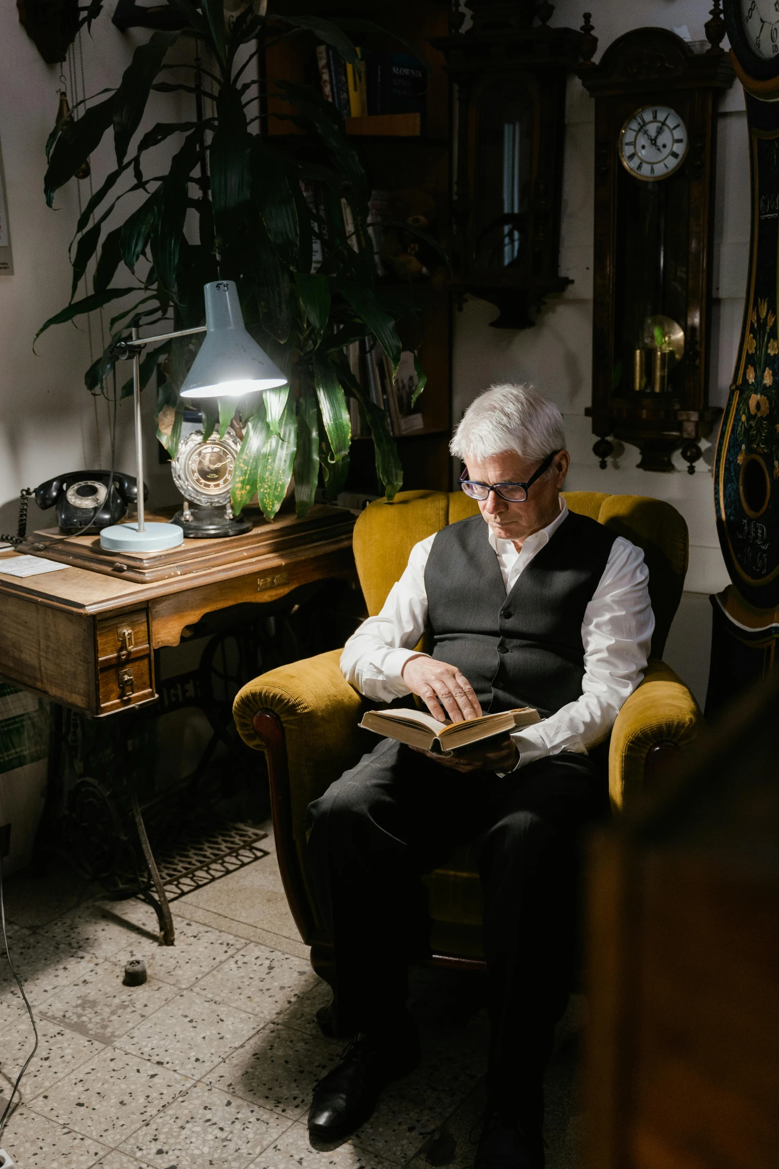 a man sitting in a chair reading a book, dark grey haired man, nostalgic lighting, wearing reading glasses, - 9