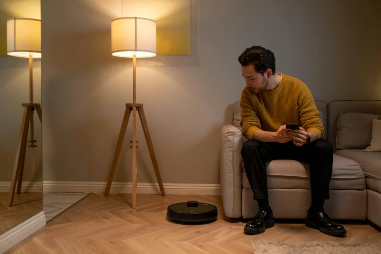 a man sitting on a couch looking at his phone, inspired by Peter de Sève, niko oneshot riding a roomba, light lighting side view, stand on stone floor, detailed product image