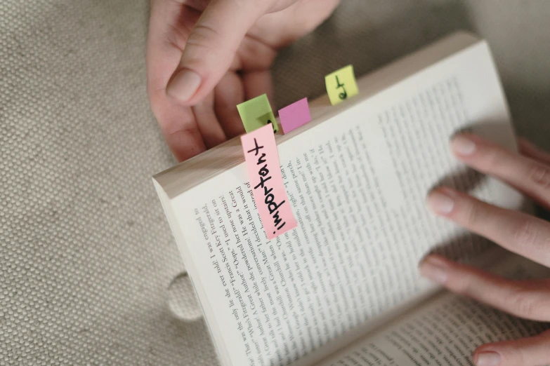 a person holding a book with sticky notes on it, neon pink, medium-shot, alternate angle, felt