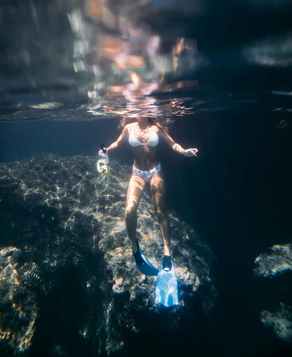 a woman in a bikini standing on a rock in the water, an album cover, unsplash contest winner, scuba mask, jelly glow, bali, no watermarks