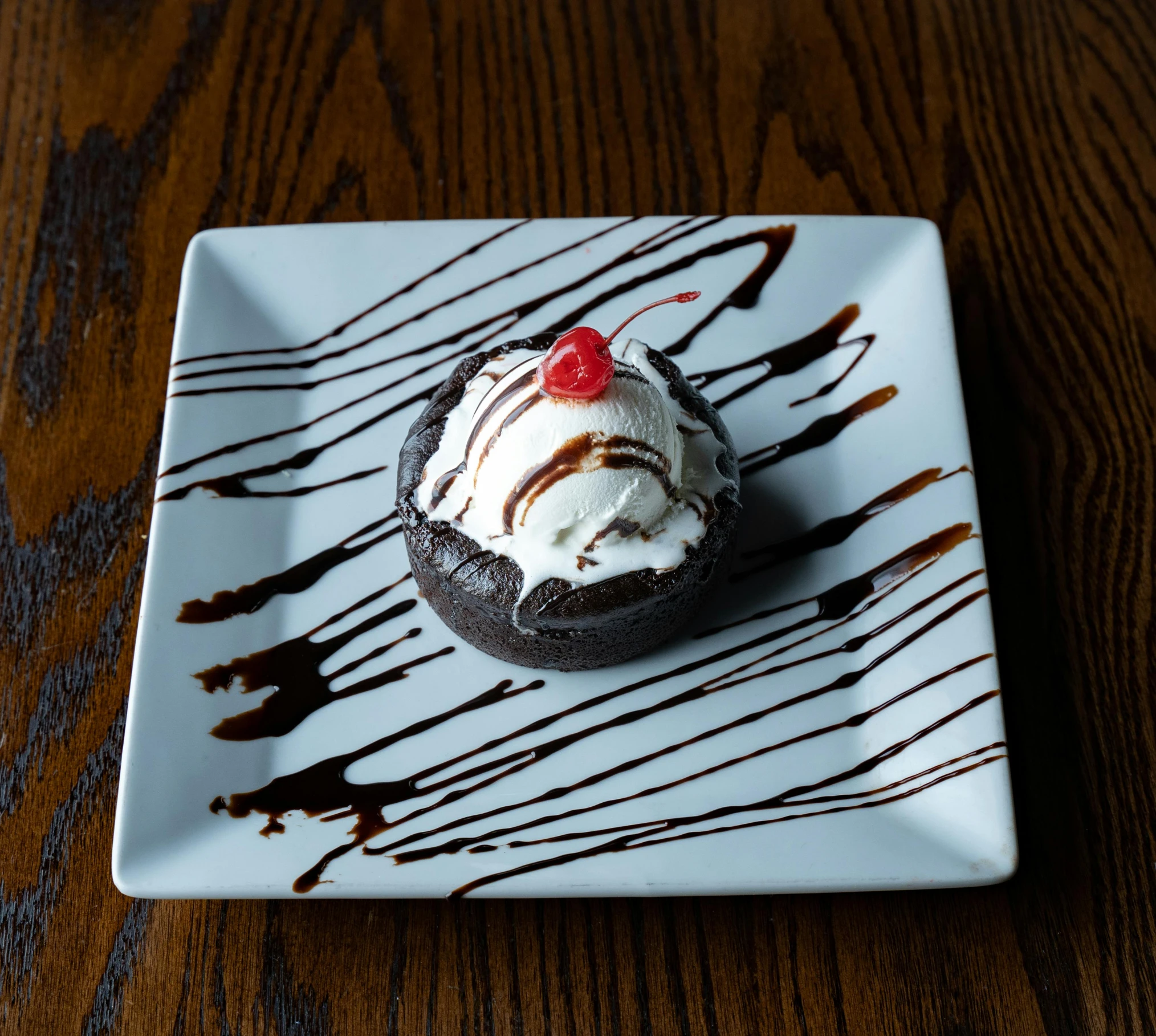 a chocolate cupcake with ice cream and a cherry on top, circle pit, smothered in melted chocolate, daily specials, sauce