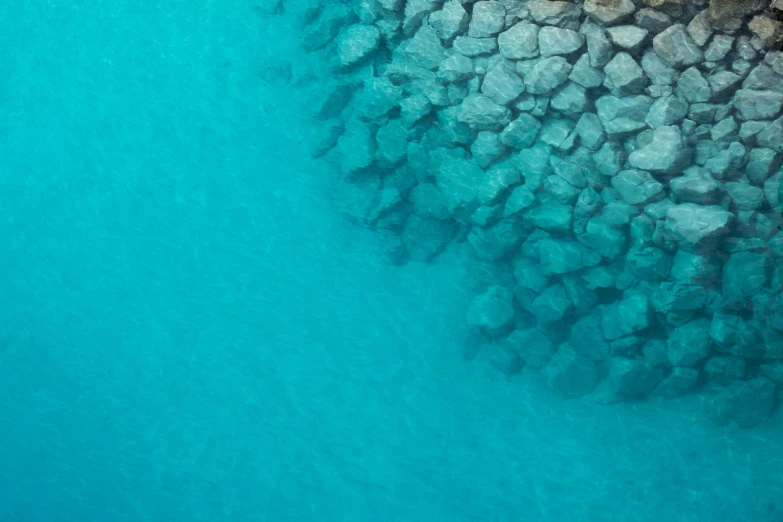 a large body of water surrounded by rocks, by Carlo Randanini, unsplash, minimalism, coral sea bottom, picton blue, 8k detail, rock wall
