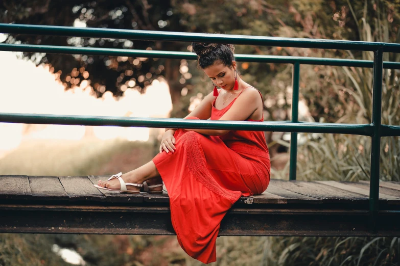 a woman in a red dress sitting on a bridge, pexels contest winner, justina blakeney, relaxed expression, alanis guillen, long dress