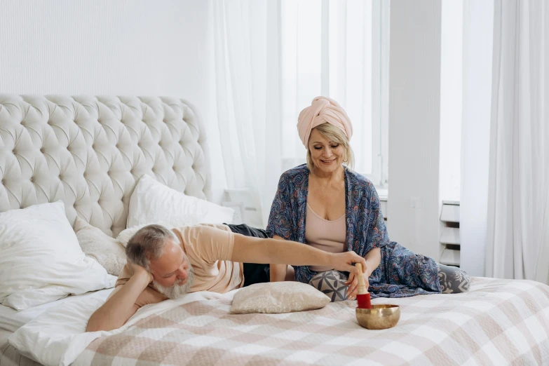 a woman laying on top of a bed next to a man, by Matija Jama, pexels contest winner, hurufiyya, middle aged, paradise garden massage, sitting on bent knees, gif