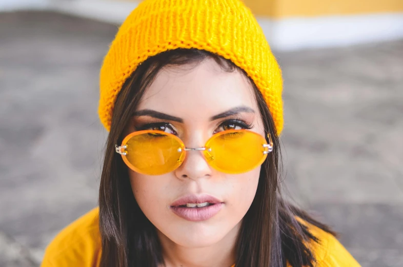 a woman wearing a yellow hat and sunglasses, inspired by Elsa Bleda, trending on pexels, yellow - orange eyes, teenager girl, charli xcx, square rimmed glasses