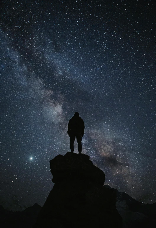 a man standing on top of a mountain looking at the night sky, looking towards camera, cosmic scale, profile picture, dark skies