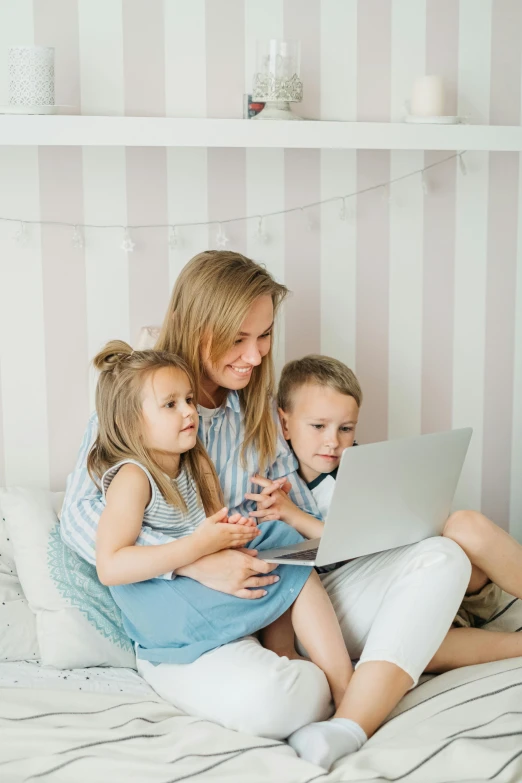 a woman and two children sitting on a bed with a laptop, pexels contest winner, happening, striped, ekaterina, 1x, low quality photo