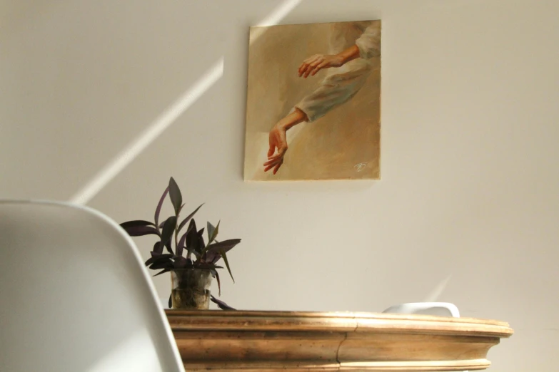 a white chair sitting next to a painting on a wall, a painting, by Eglon van der Neer, unsplash, figurative art, hands on counter, delicate soft hazy lighting, emanating magic from her palms, on a wooden table