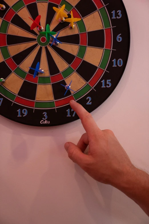 a close up of a person pointing at a dart on a wall, game, on display, cooked, multicoloured