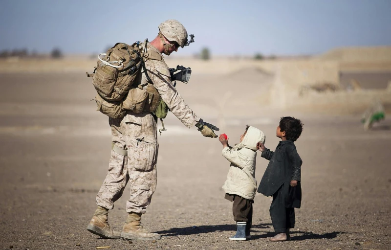 a soldier holding a small child's hand, a colorized photo, by Bradley Walker Tomlin, pexels contest winner, desert camouflage, giving gifts to people, marine armor, marc newsom