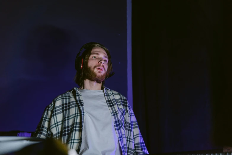 a man wearing headphones standing in front of a keyboard, unsplash, process art, asmongold, concert footage, portrait mode photo, calm night. over shoulder shot