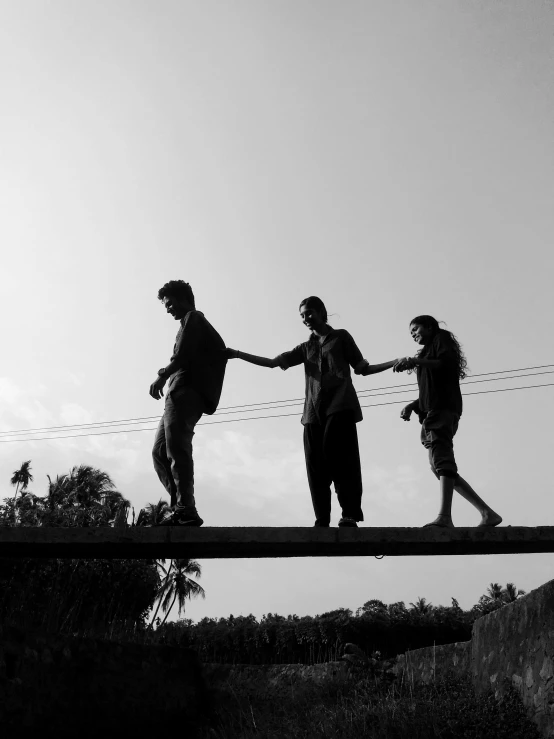 a group of people walking across a bridge, by Max Dauthendey, kerala village, high contrast!!, broken down, holding each other